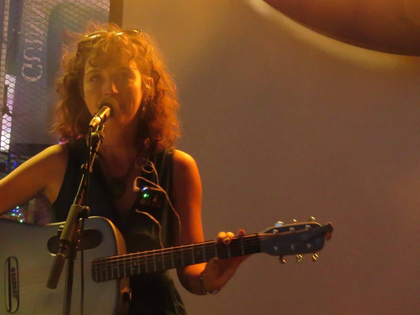Chanteuse guitariste en concert, lumière chaude