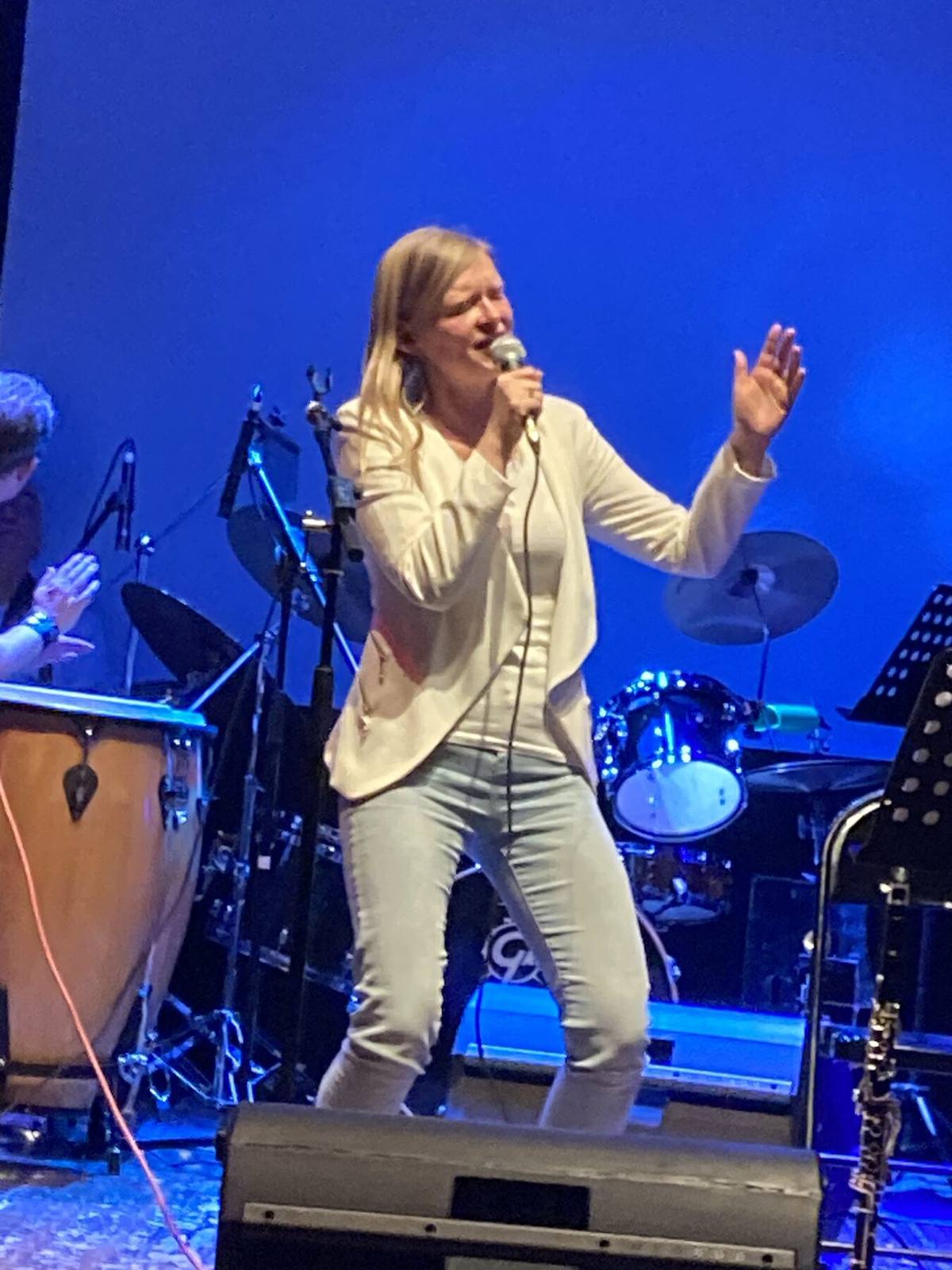 Concert sur scène avec lumières bleues, chanteuse au micro